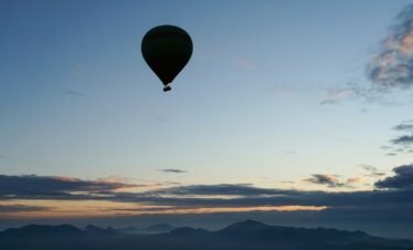 a hot air balloon flying over a mountain range