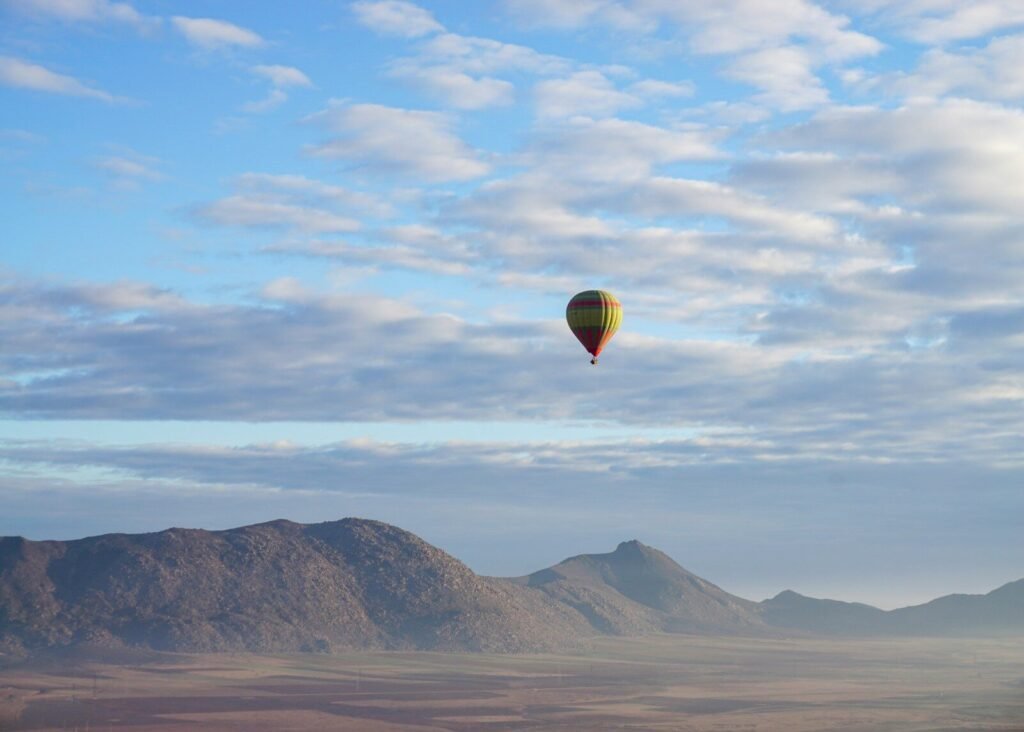 a hot air balloon flying over a mountain range