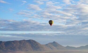 a hot air balloon flying over a mountain range