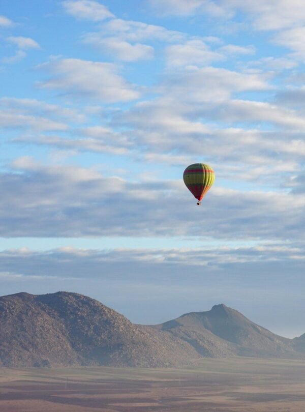 a hot air balloon flying over a mountain range