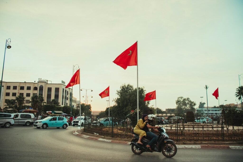 A man riding a motorcycle down a street next to red flags