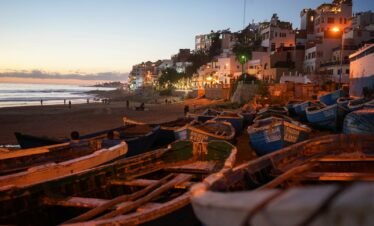 boats on seashore near houses